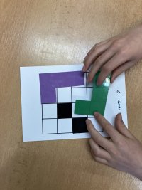 L hra - ve dvojicích, každý přesune tvar L své barvy a oba černé čtverce na libovolné volné pole